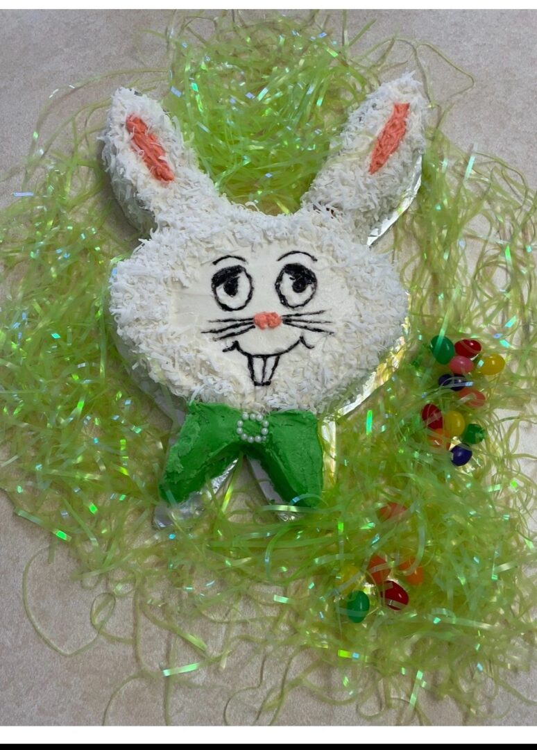 A cute white bunny face with a green bow on a textured green background.