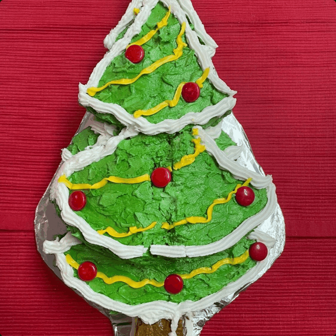 A Christmas tree-shaped cookie decorated with green icing and colorful candies.