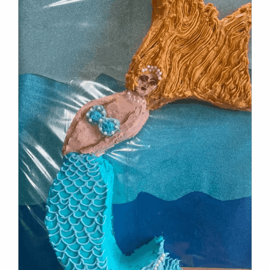A baby dressed as a mermaid lying on a blue backdrop.