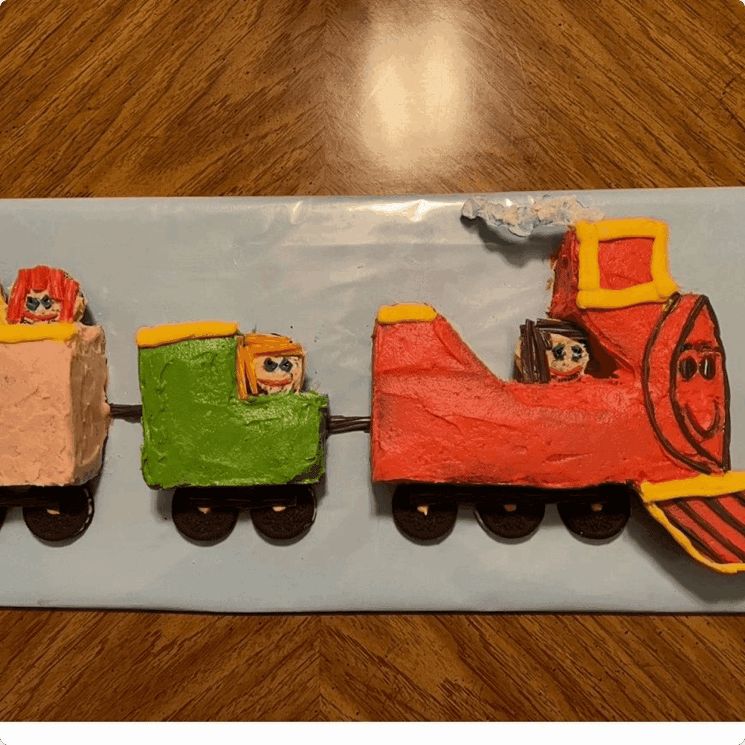 Three train-shaped cakes with colorful icing and faces on them.