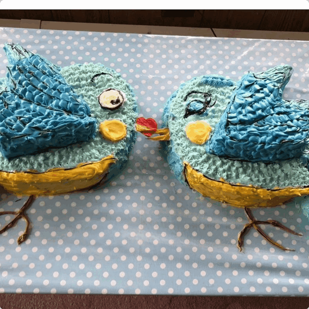 Two crocheted blue bird toys with button eyes on a polka-dot surface.