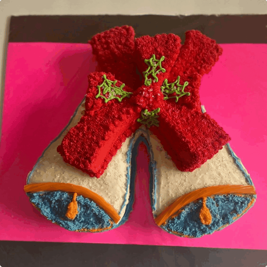 Handmade baby booties with red bows on top, set against a pink background.