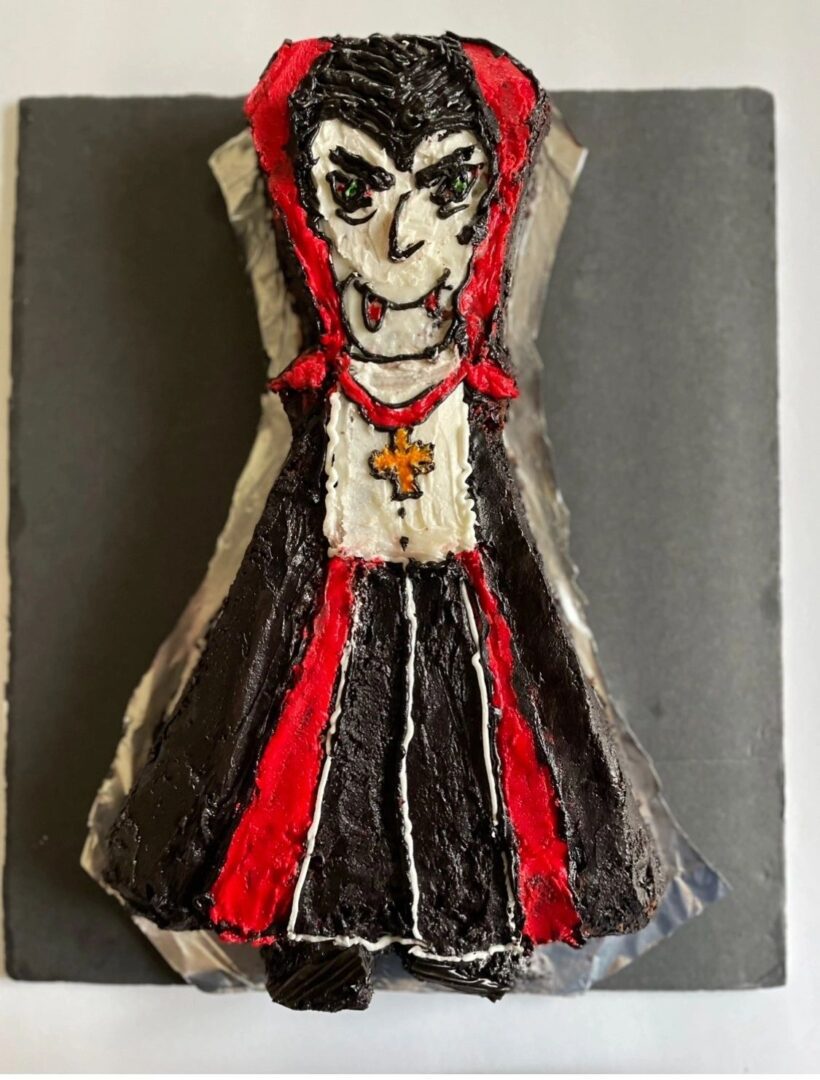 A handcrafted doll with a striking red and black dress and an intense facial expression.
