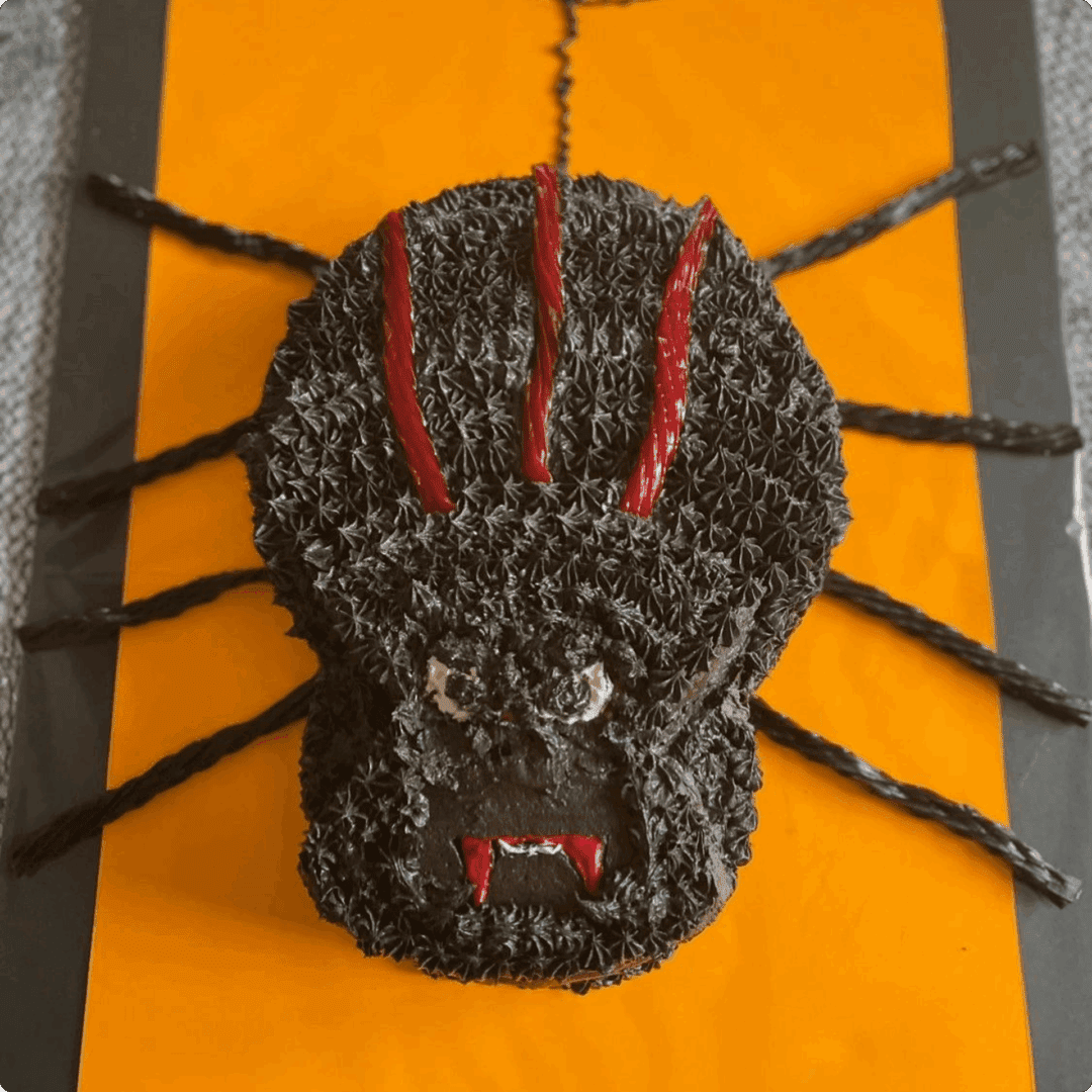 Close-up of a spider-shaped knitted figure with red accents on an orange background.
