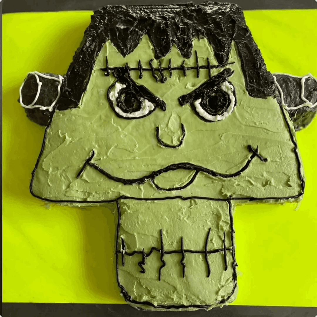 A green cake decorated like Frankenstein's monster with black icing details.