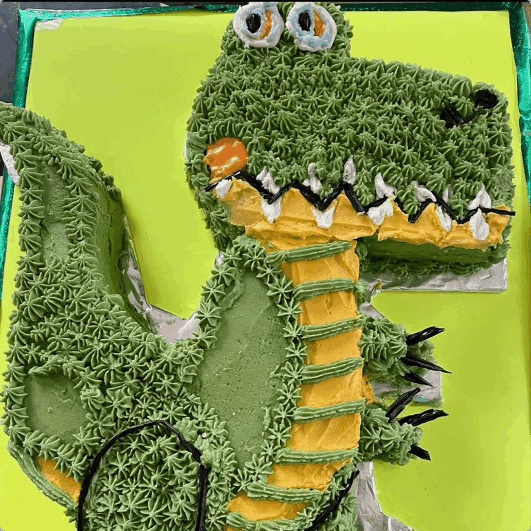 A green crocheted dragon with orange and yellow accents.