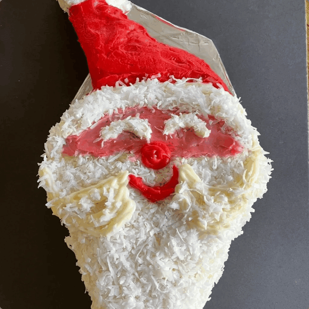 A Santa Claus face made of cake with red and white frosting.
