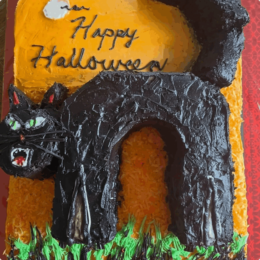 Halloween cake decorated with a black cat and "Happy Halloween" message.