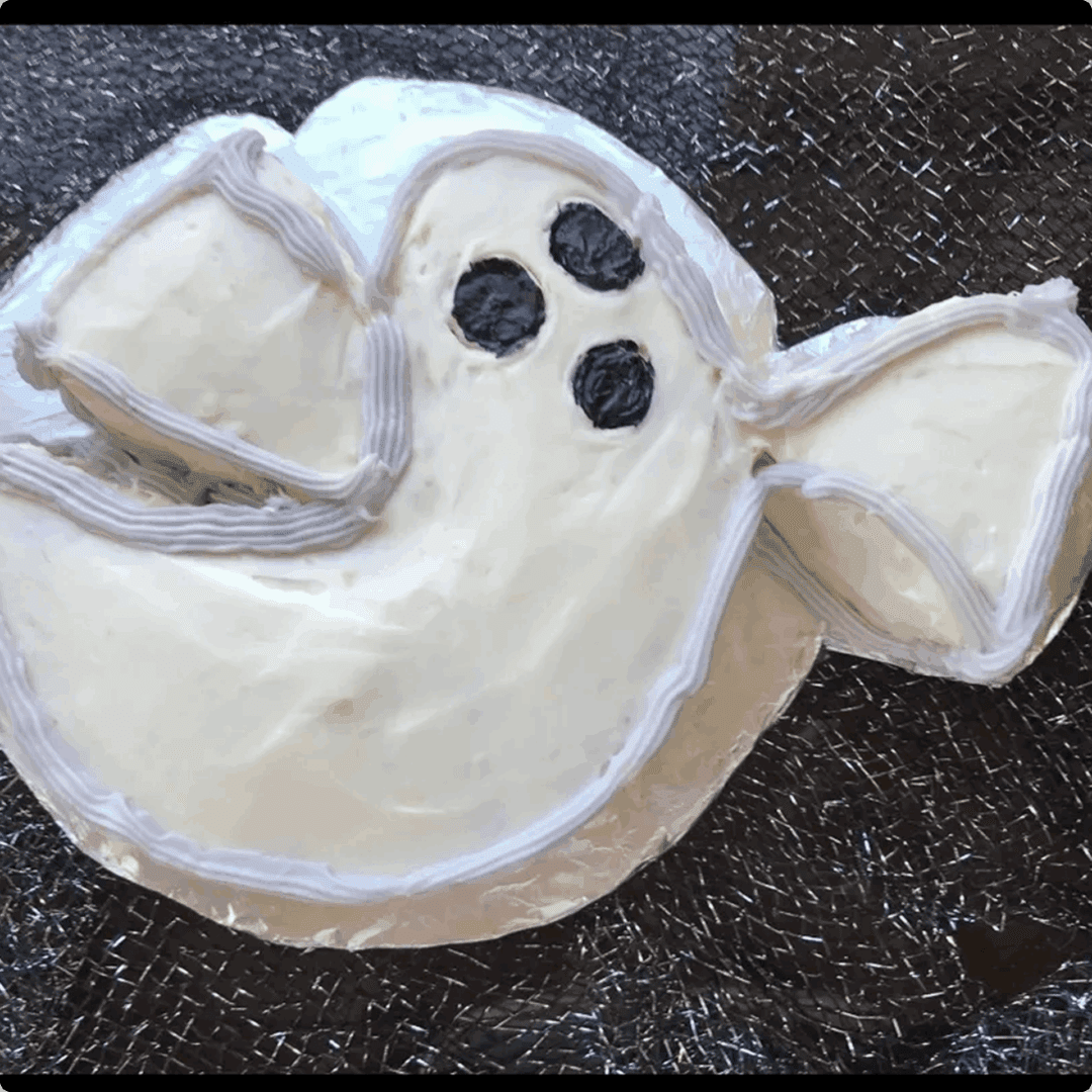 A ghost-shaped cookie with white icing and black eyes and mouth.